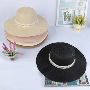 Detail of wide brim straw sun hats with elegant pearl and gold chain decorative bands