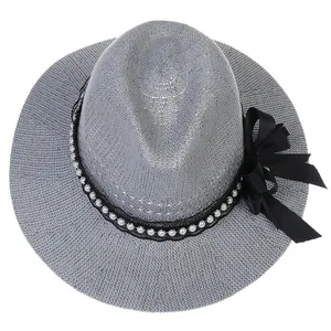 Detail of grey woven fedora straw hat with pearl trim and elegant black bow decoration