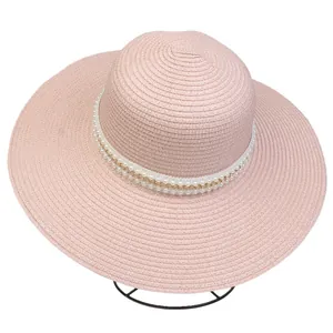 Detail of pink straw hat featuring decorative white pearls and a gold chain strap