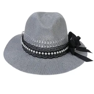 Close-up of gray woven sun hat featuring black lace, pearls, and a satin bow detail