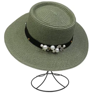 Detail of green boater hat featuring black velvet ribbon, pearls, and floral ornaments