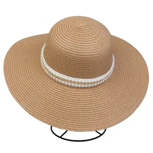 Detail of wide brim straw hat with elegant faux pearls and golden chain decoration