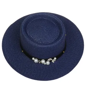 Detailed close-up of dark blue straw boater hat with white pearls and flower ornaments
