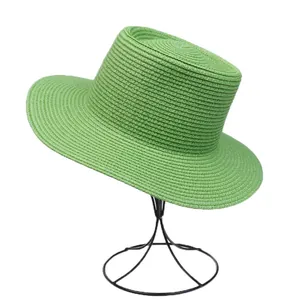Detail of bright green straw hat with spiral weave on minimalist display stand