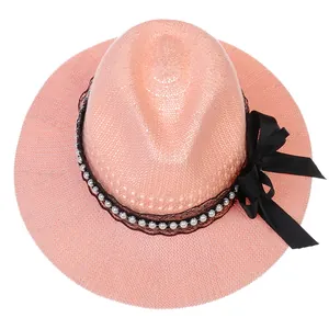 Close-up of pink straw hat featuring black lace, white pearls and a large silk bow