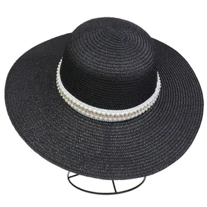 Detail of wide brim straw hat with double-row pearl and gold chain decorative band