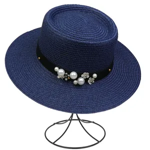 Detail of navy straw hat featuring elegant faux pearls and floral embellishments