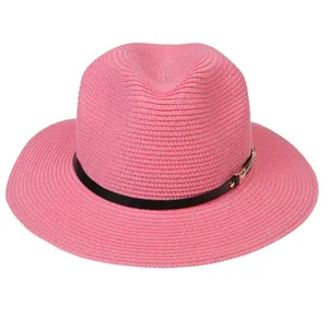 Détail de la texture d'un chapeau de paille rose avec lanière en cuir noir et boucle