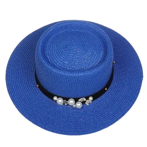 Detailed view of blue boater hat with black ribbon, white pearls and floral accents