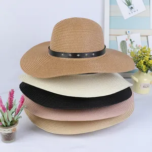 Detailed close-up of straw sun hats in multiple colors with metallic star rivets decorations