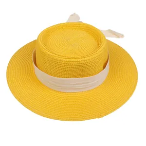 Detailed top view of a yellow woven straw boater hat with a chic beige ribbon bow