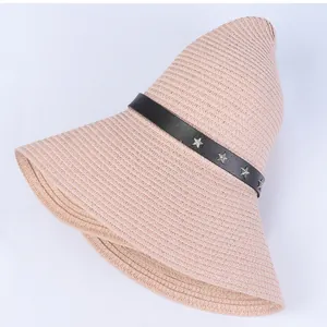 Detail of light pink straw sun hat featuring a star-studded black leather band