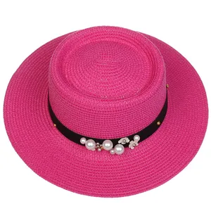 Detail of rose pink boater straw hat with black ribbon, white pearls and floral decoration