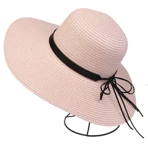 Detail of pink straw sun hat featuring a black decorative band and chic bow tie accent