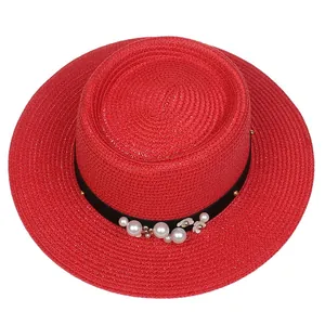 Detail of red straw hat featuring elegant white pearls and floral trim on a black band