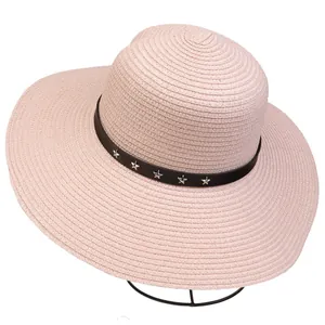 Detail of pink straw sun hat featuring black leather band with silver star metal rivets
