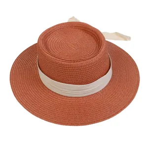 Close-up of brick red straw boater hat with ivory ribbon for summer beach vacation