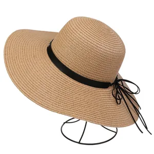 Detail of khaki wide brim straw hat with black ribbon bow on a minimalist metal stand