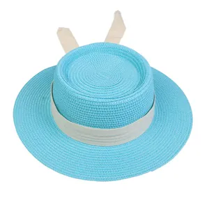 Close-up of sky blue straw boater hat featuring a cream ribbon with bunny ear accents