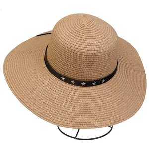 Close-up of khaki straw sun hat with black band and silver star studs on metal stand