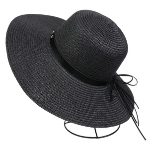 Detail of black wide-brim straw hat featuring silver stud ribbon and a bow tie back