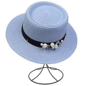 Detailed view of light blue woven sun hat with black ribbon and white pearl floral accents