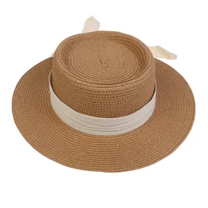 Detailed view of brown straw boater hat with cream ribbon and bow on white background