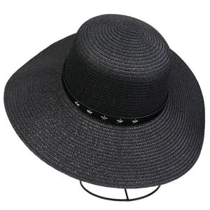 Detail of black woven straw sun hat featuring a leather band with silver star metal studs