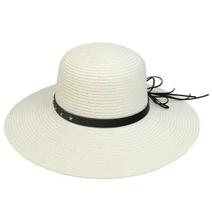 Detail of a straw sun hat featuring a black band with silver star studs and tassels