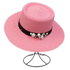 Detail of pink boater hat with black ribbon, white pearls and floral ornaments