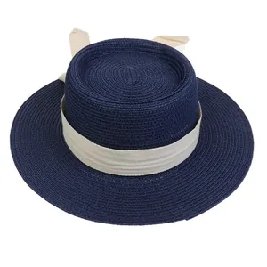 Detail of navy straw hat featuring a chic beige herringbone ribbon and rear bow accent