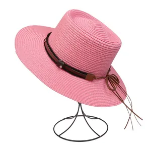 Detail eines rosa Strohhuts mit braunem Nietband und strukturierter Weboberfläche