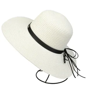 Detail view of white straw sun hat featuring black leather band and tiny metal stars