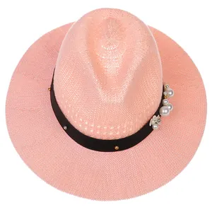 Detailed view of pink fedora with black ribbon featuring pearls and metallic studs decoration