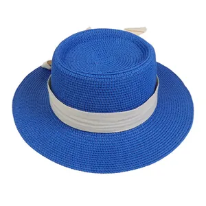 Detail of blue straw boater hat featuring fine woven texture and beige herringbone ribbon