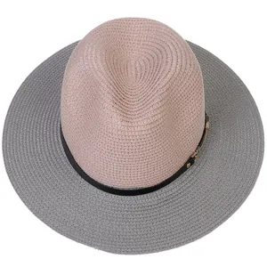 Close-up of pink and grey woven Panama hat with black band and gold buckle detail