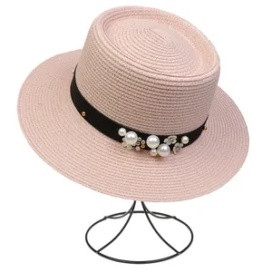 Detail of pink straw sun hat featuring elegant black ribbon with pearls and flower accents