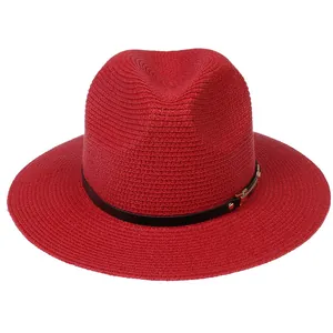 Détail d'un chapeau de paille rouge avec texture tissée et bande noire à boucle en métal