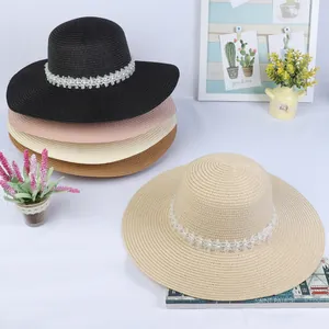Detail of colorful straw sun hats featuring elegant floral lace and pearl trim decorations