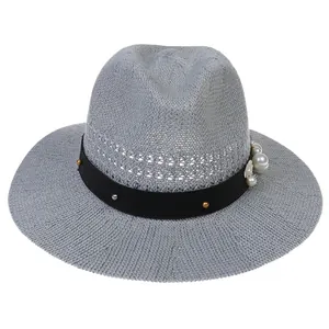 Detail of grey hollow straw hat with pearl accents, metal studs and small white flower decor