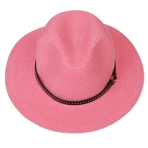 Detailed close-up of a pink woven straw fedora hat with a black studded leather band