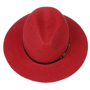 Détail d'un chapeau Panama rouge avec ruban en cuir noir et boucle en métal doré
