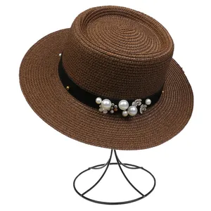 Detail of a brown straw hat featuring a black ribbon with pearls and floral ornaments