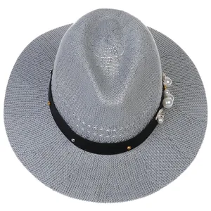 Close-up of gray hollow straw hat with black rivet ribbon and faux pearl flower detail