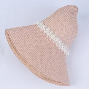 Detail of pink straw sun hat featuring elegant white lace trim and pearl embellishments