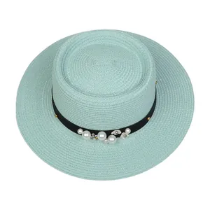Detailed top view of mint green straw hat with pearl flowers and black grosgrain ribbon