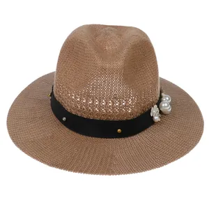 Detailed texture of straw fedora hat featuring black ribbon with pearls and floral accents