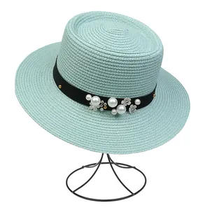 Detailed close-up of mint green straw hat featuring pearl flower and black ribbon decor