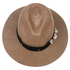 Detail view of woven straw sun hat featuring black band with pearls and floral ornaments