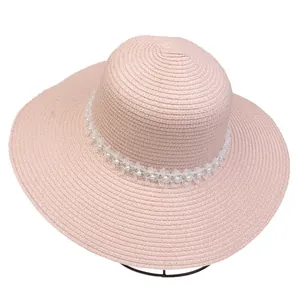 Detailed close-up of pink woven straw hat featuring elegant lace trim and pearl accents